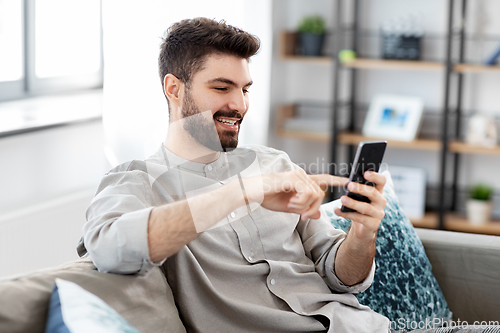 Image of happy smiling young man with smartphone at home