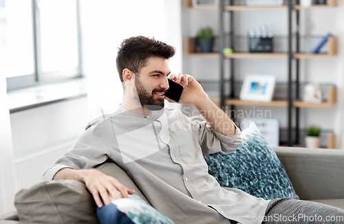 Image of happy man calling on smartphone at home