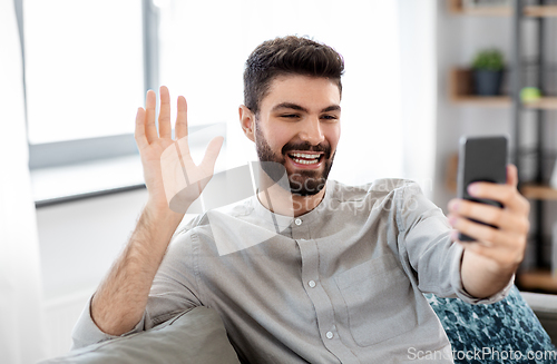 Image of man with smartphone having video call at home