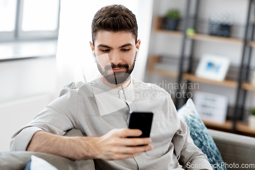 Image of man in earphones listening to music on smartphone
