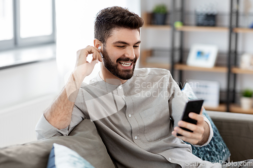 Image of man in earphones listening to music on smartphone