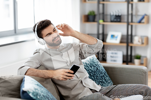 Image of man in headphones listening to music on smartphone