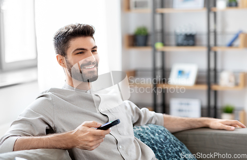 Image of happy man with remote control watching tv at home