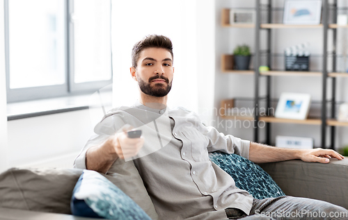 Image of man with remote control watching tv at home