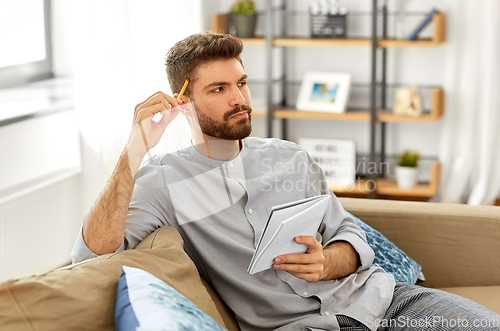 Image of man writing to notebook and thinking at home