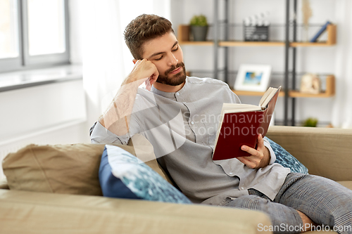 Image of man reading book at home