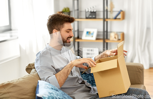 Image of happy man opening parcel box at home