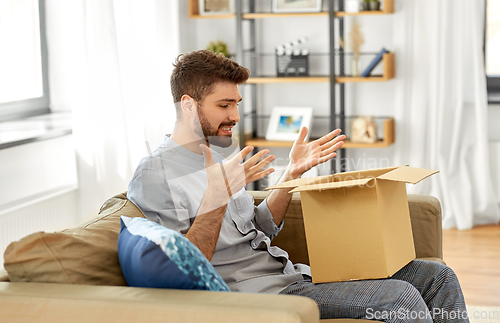 Image of disappointed man opening parcel box at home