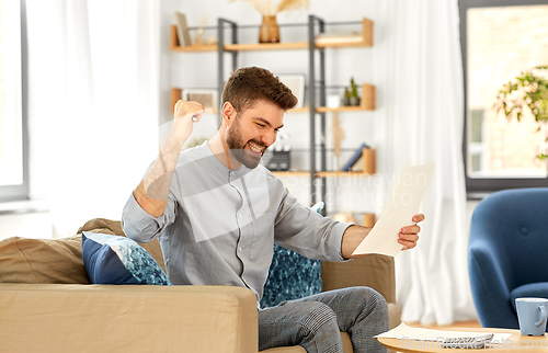 Image of man with bills counting on calculator at home