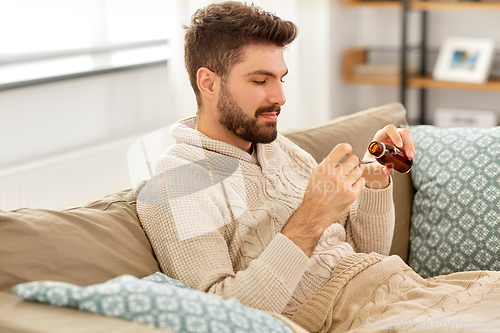 Image of sick man pouring medication from bottle to spoon