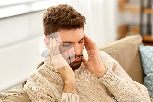 Image of unhappy man suffering from head ache at home