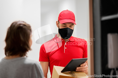 Image of delivery man in mask with tablet pc and box