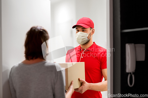 Image of delivery man in mask giving parcel box to customer