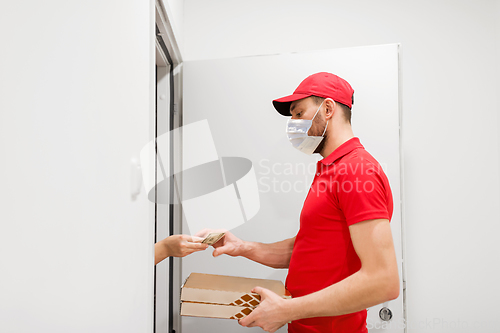 Image of delivery man in mask taking money for pizza