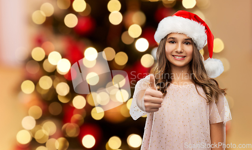 Image of happy teenage girl in santa hat showing thumbs up