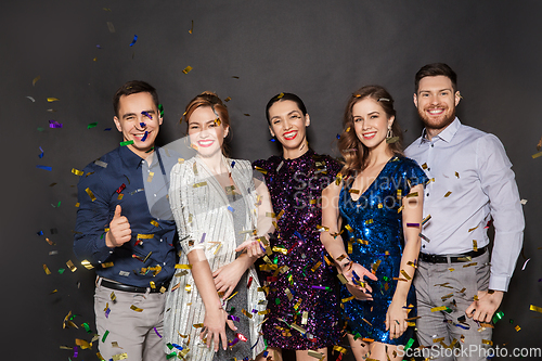 Image of happy friends at party under confetti over black