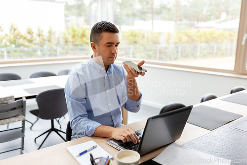 Image of man with smartphone and laptop at home office