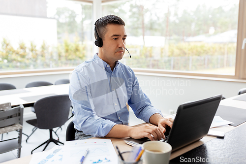 Image of man with headset and laptop working at home