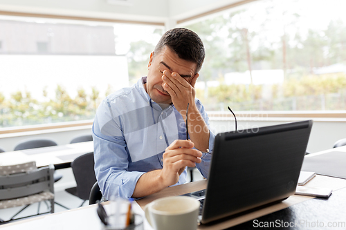 Image of tired man with laptop working at home office