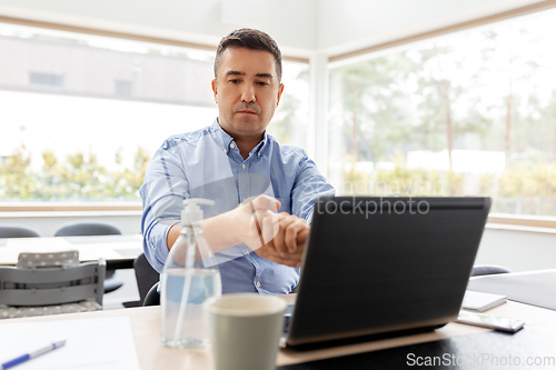 Image of man using hand sanitizer at home office