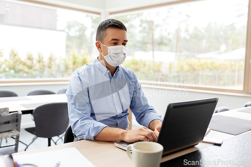 Image of man in mask with laptop working at home office