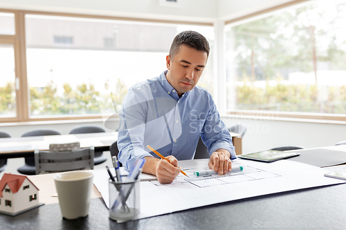 Image of architect with blueprint working at home office