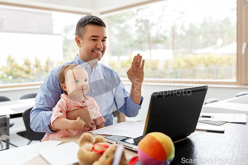 Image of father with baby working on laptop at home office