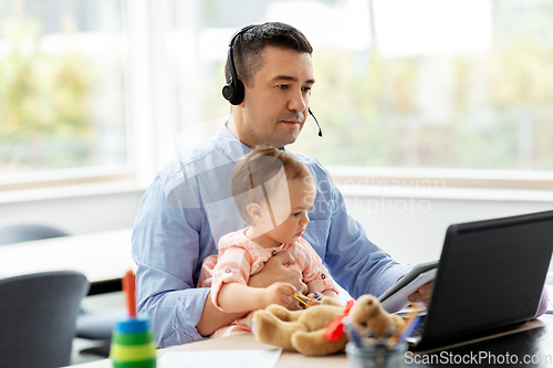 Image of father with baby working on laptop at home office