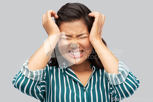 Image of stressed asian woman holding to her head