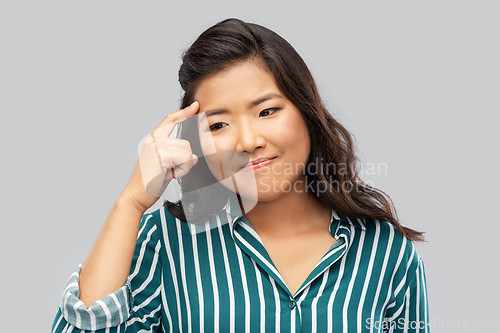 Image of thinking asian woman over grey background