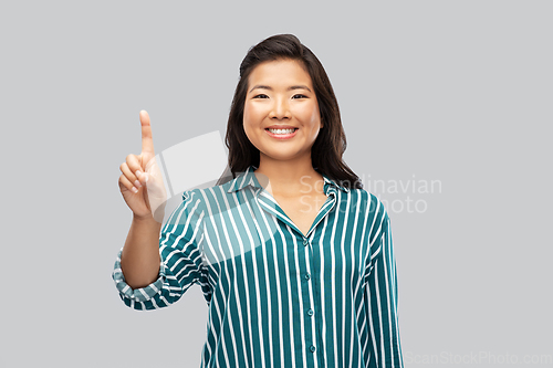 Image of happy asian woman showing one finger up