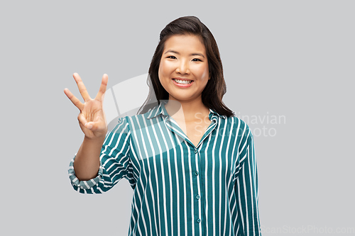 Image of happy asian woman showing three fingers