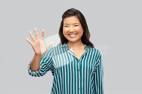 Image of happy asian woman showing five fingers