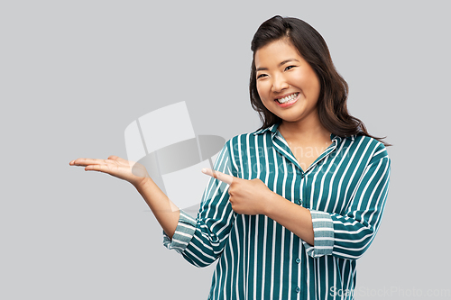 Image of happy asian woman holding something on hand