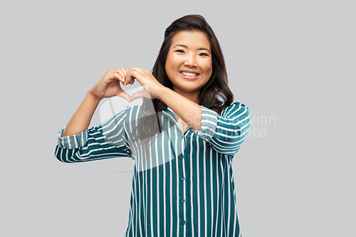 Image of happy asian woman showing hand heart gesture
