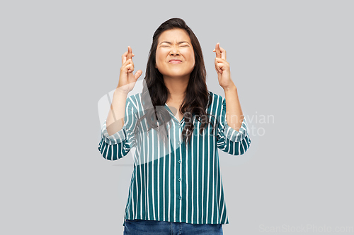 Image of asian woman holding fingers crossed