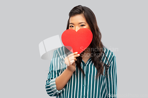 Image of happy asian woman covering face with red heart