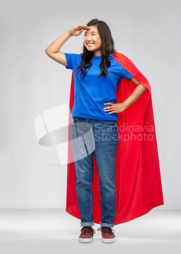 Image of asian woman in superhero cape looking far away