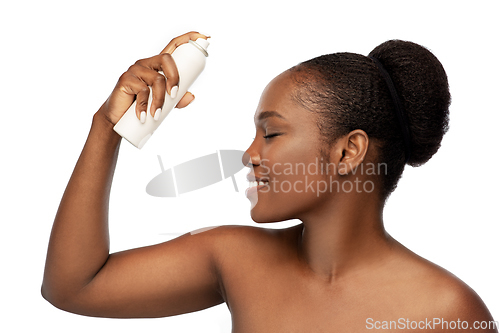 Image of beautiful young african woman spraying facial mist