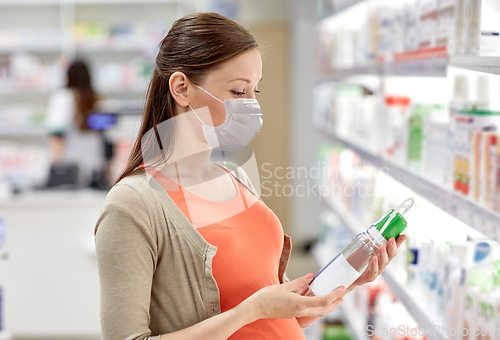 Image of pregnant woman in mask choosing lotion at pharmacy