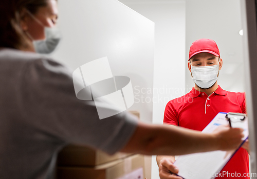 Image of delivery man in mask and customer signing papers