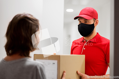 Image of delivery man in mask giving parcel box to customer