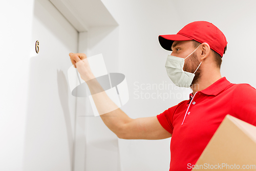 Image of delivery man in mask with parcel knocking on door