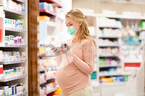 Image of pregnant woman in mask with medicine at pharmacy