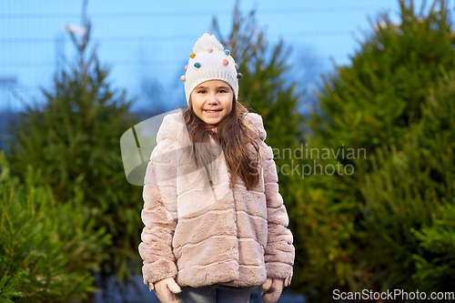 Image of little girl choosing christmas tree at market