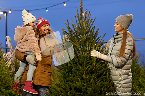 Image of happy family choosing christmas tree at market