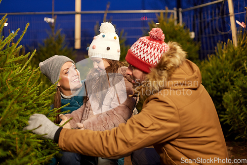 Image of happy family choosing christmas tree at market