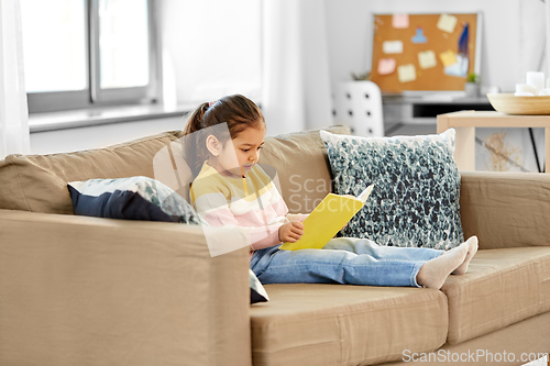 Image of little girl reading book at home