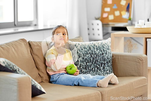 Image of little girl with apple sitting on sofa