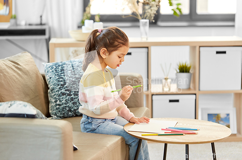 Image of little girl drawing with coloring pencils at home